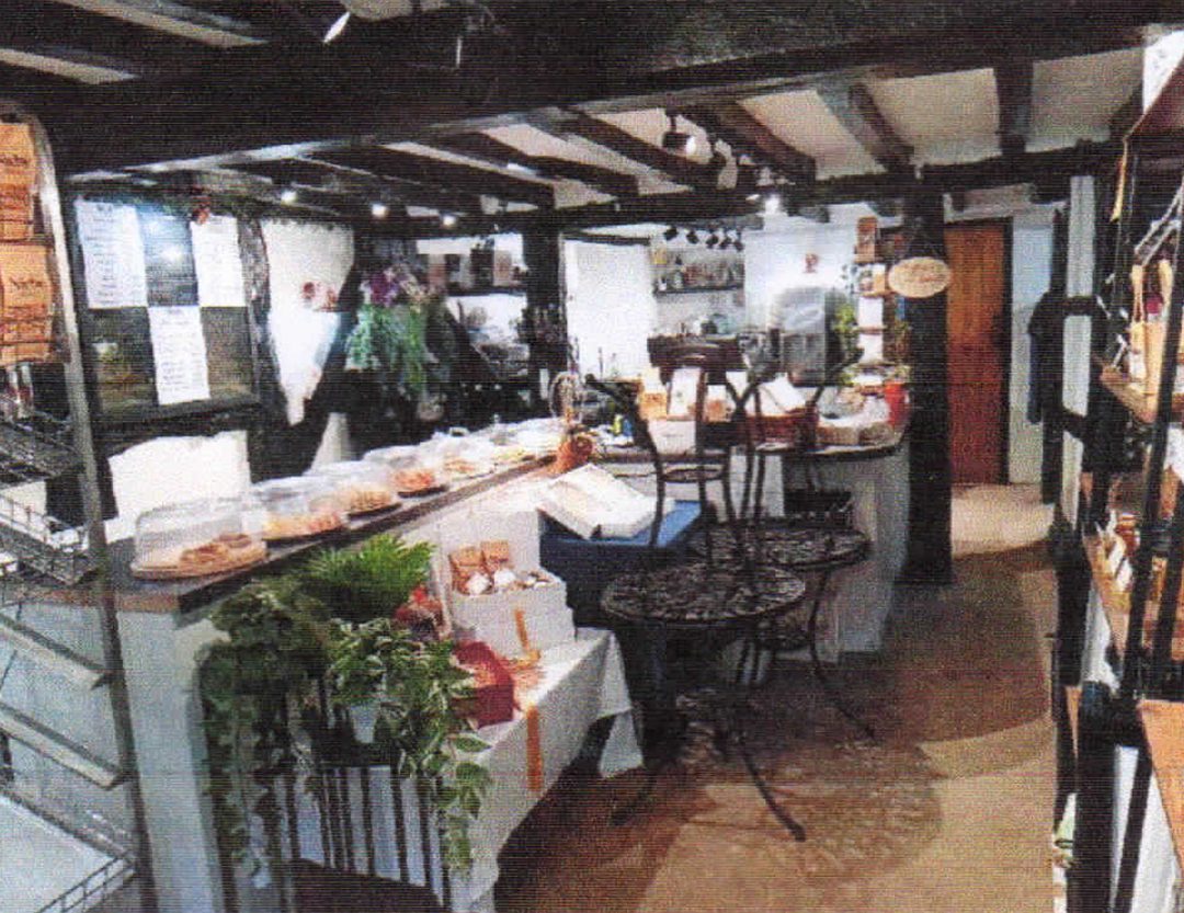 Empty commercial property interior featuring historic dark wooden ceiling beams and character features. The open layout includes a long counter area with white panelling, exposed structural timbers, and neutral flooring, showing the potential for flexible retail or office use.
