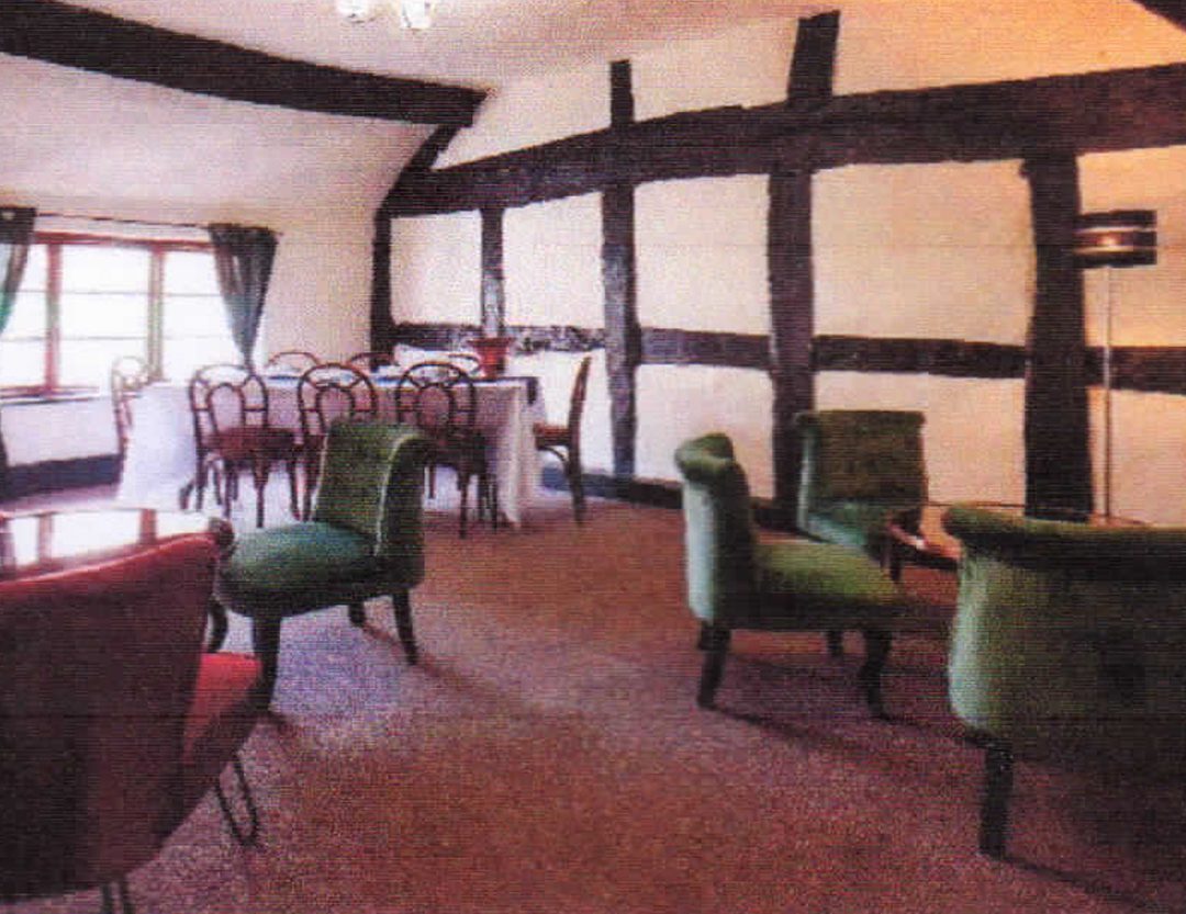 A large first-floor room featuring dramatic, authentic Tudor-style dark wall beams and a sloped ceiling. The bright space benefits from a wide window at the far end and open floor area, illustrating its potential as a meeting room, office, or function space.